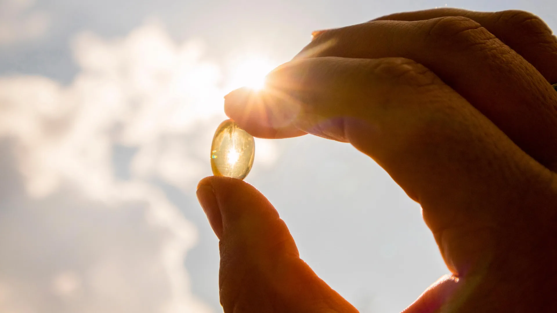 A person holding a vitamin D supplements in natural sunlight, representing winter wellness, reduced seasonal sun exposure, and immune health support.